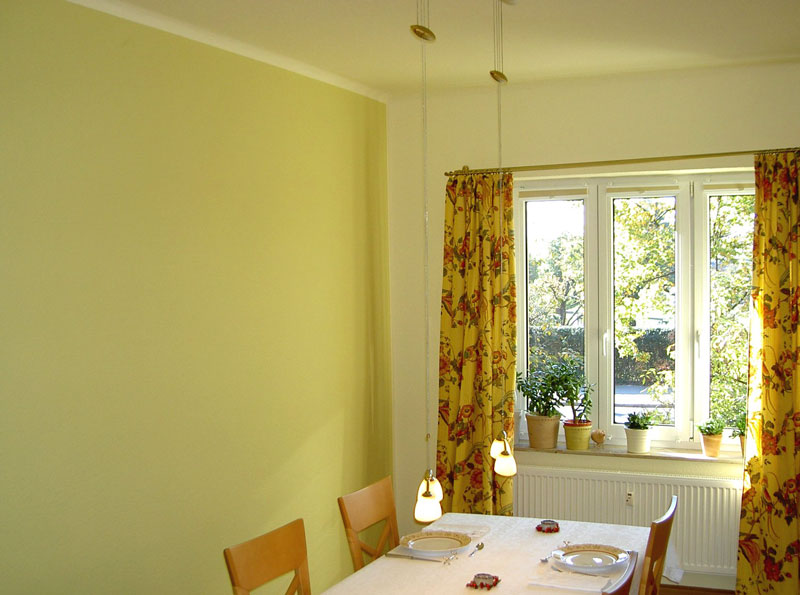 Esszimmer mit gelb gestrichenen Wänden und floralen Vorhängen